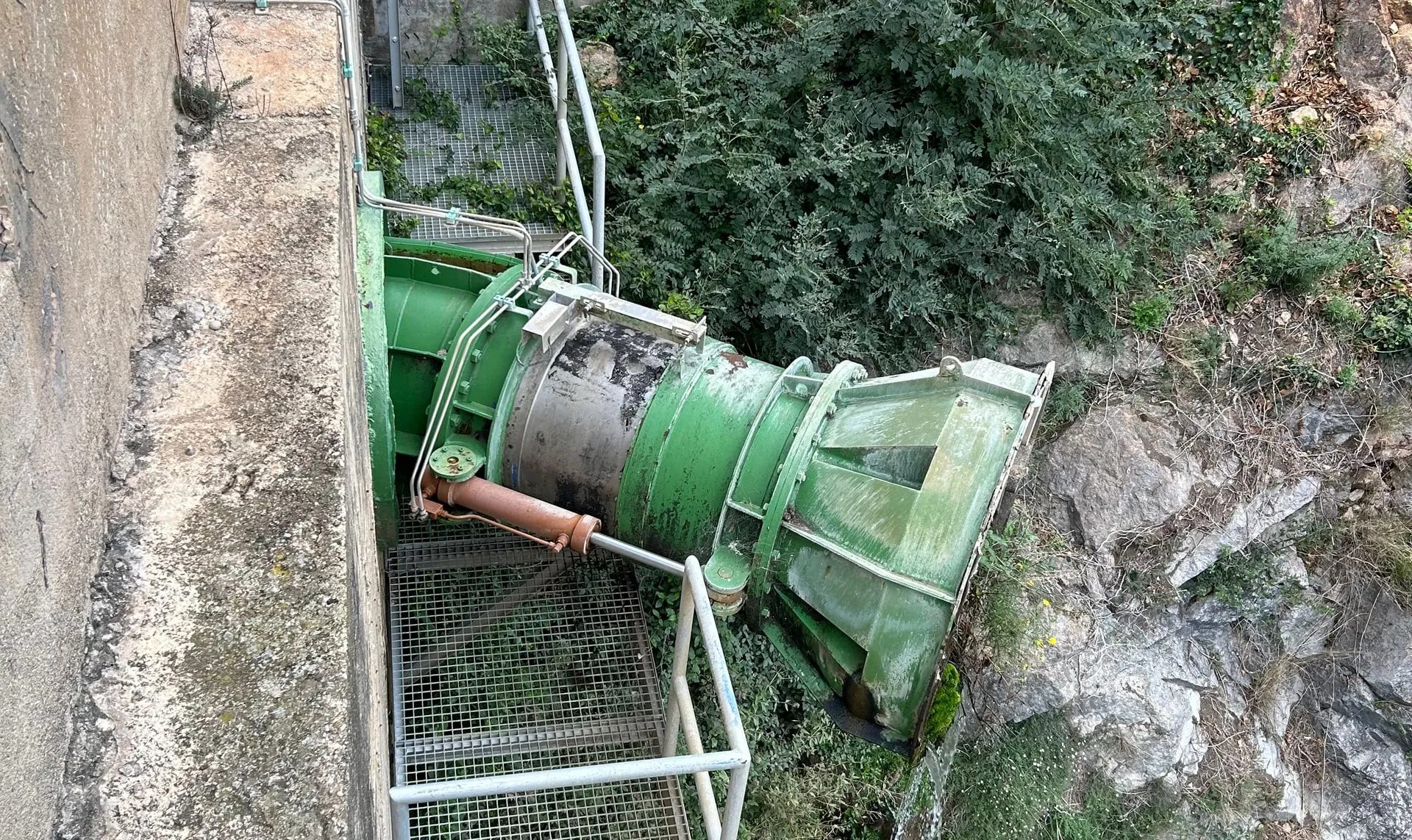 Turbina hidráulica pintada de verde sobre estructura de hormigón